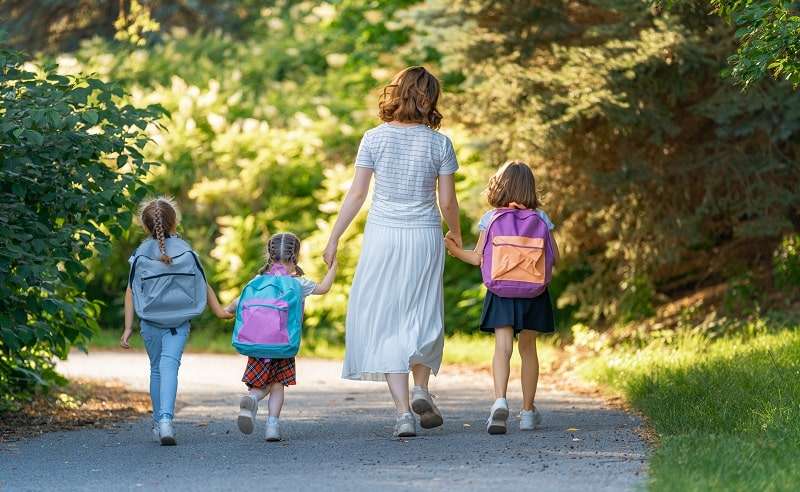 Tortendeko Einschulung - glückliche Kinder werden von der Mutter in die Schule gebracht