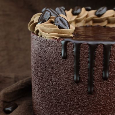 Köstlicher Mokkakuchen mit braunem, samtigem Überzug, Kaffeesahne und Schokoladen-Kaffeebohnen.